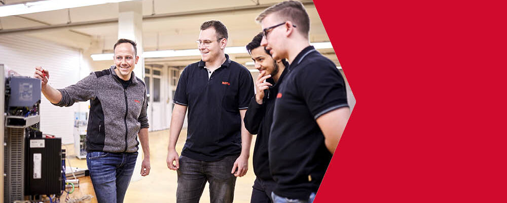 Vier Männer im Kreis stehend die verschiedene elektronische Geräte begutachten