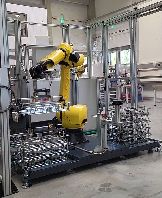 Ein kollaborativer Roboter stapelt Stahlkörbe präzise aufeinander in einer Industriehalle