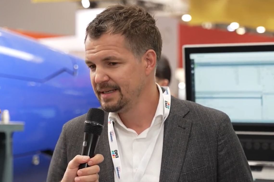 Einem Mann im Vordergrund wird ein Mikrofon vorgehalten und interviewt.